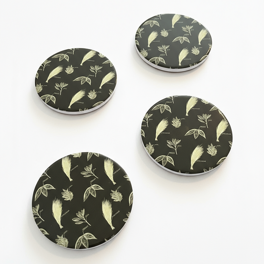 Four round coasters with a nature-themed design on a white background